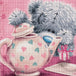 Diamond Painting mit grauem Teddy hinter einer Teekanne mit Herzmuster und kleinem Geschenk. Mockup.