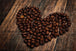 Diamond Painting mit Kaffeebohnen in Herzform auf dunklem Holztisch. Mockup.