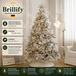 Schneebedeckter kuenstlicher Weihnachtsbaum in Creme-Weiss mit warmen Lichtern und eleganter Weihnachtsdekoration