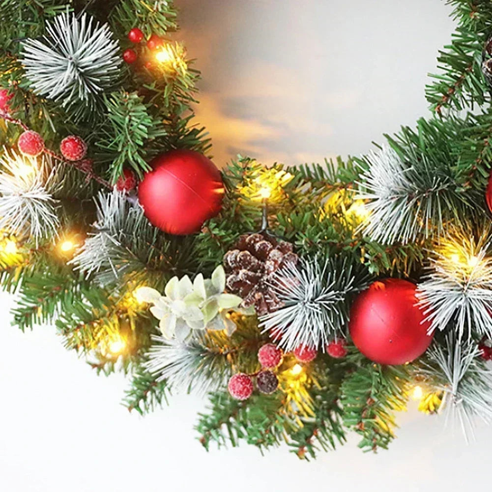 Detailansicht des Weihnachtskranzes mit Tannengrün, roten Kugeln, Tannenzapfen und warmweißen LED-Lichtern