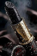 Diamond Painting mit schwarzem Lippenstift in goldener Hülse und glänzenden Wassertropfen