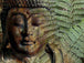 Diamond Painting eines Buddhas aus Stein, der teilweise von grünen Farnblättern verdeckt wird. 
