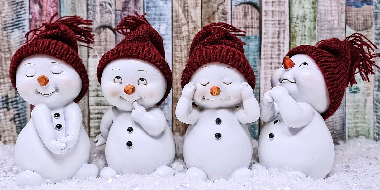 Diamond Painting von vier kleinen Schneemann-Figuren mit roten Mützen vor einer bunten Holzwand im Schnee. 
