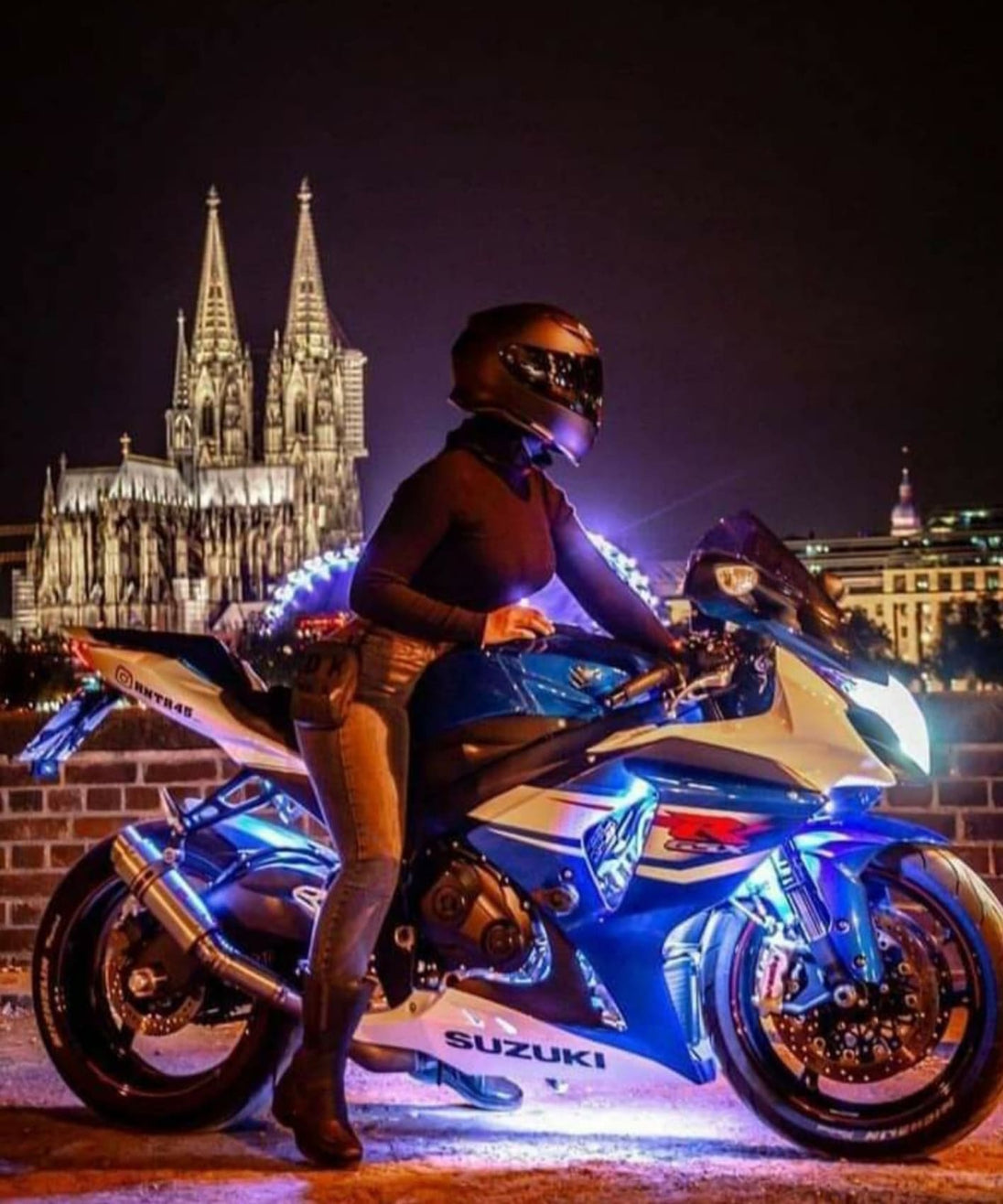 Diamond Painting einer Frau auf einem blauen Motorrad bei Nacht vor dem beleuchteten Kölner Dom. 
