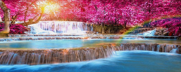 Diamond Painting eines stufigen Wasserfalls im pinken Wald mit einem Regenbogen. 
