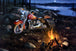 Diamond Painting eines roten Motorrads an einem Lagerfeuer bei Nacht an einem See unter dem Vollmond.