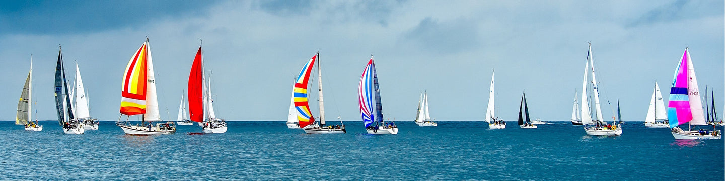 Diamond Painting einer Regatta mit vielen bunten Segelschiffen auf blauem Wasser unter bewölktem Himmel.

