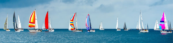 Diamond Painting einer Regatta mit vielen bunten Segelschiffen auf blauem Wasser unter bewölktem Himmel.
